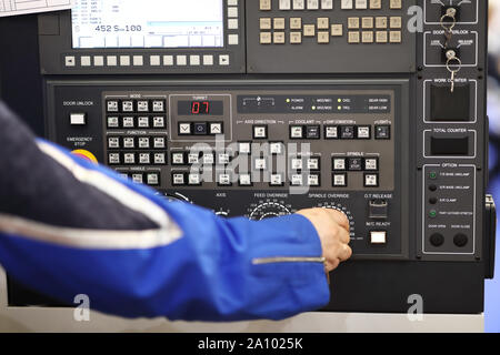Operator adjusts the parameters of CNC machine operation. Selective focus. Stock Photo