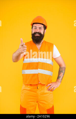My work will be sure to impress. Construction worker in work clothes pointing finger on yellow background. Building engineer or builder at work. Building and construction work. Stock Photo