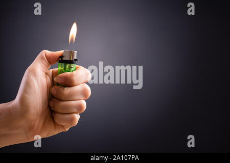 Close up woman hand holding a burning lighter in the dark background. Stock Photo