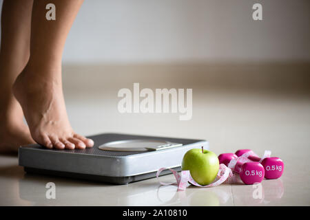 Measure tape with dumbbells and weight scale on the pink