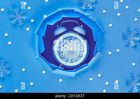 Happy New Year 2020! Aarm clock in paper hole, flat lay on vibrant blue color paper Stock Photo