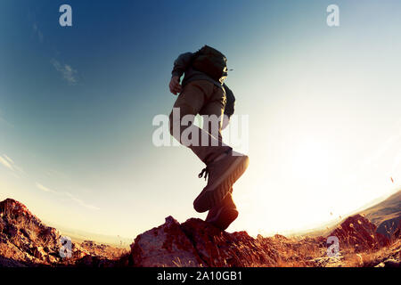 Silhouette of walking hiker with backpack in sunset light at mountains area. Closeup photo Stock Photo