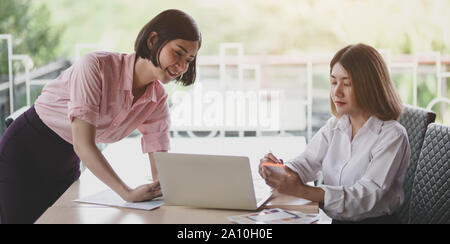 Two young professional UI graphic designers discussing on their smartphones templates together Stock Photo