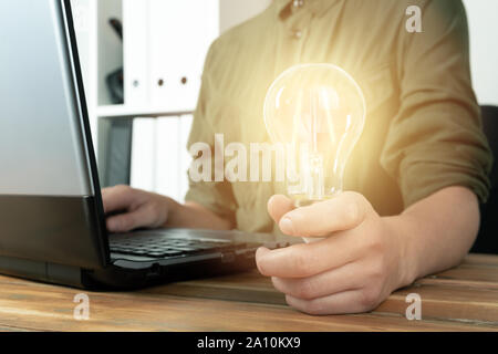 Business woman hand holding lightbulb in office. Concept saving energy, idean and creativity Stock Photo