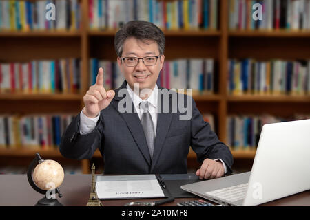 A portrait of an Asian middle-aged male businessman sitting at a desk Stock Photo