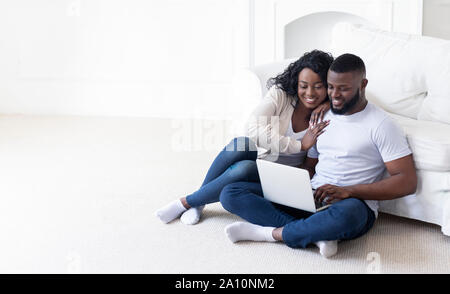 African american couple sitting on floor with laptop Stock Photo