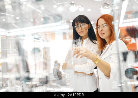 ginger girl pointing to the glass window, choosing a product, item to buy, two women doing shopping, lifestyle, copy space Stock Photo