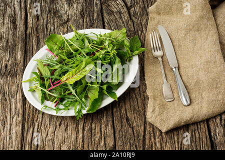 Healthy food concept. Green salad on rustic background with cutlery on canvas. Flat lay Stock Photo
