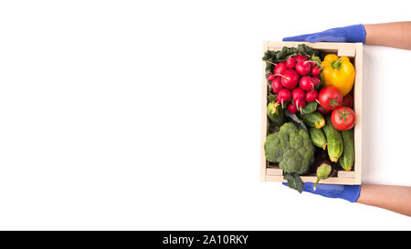 Woman in rubber gloves giving big wooden box with vegetables Stock Photo