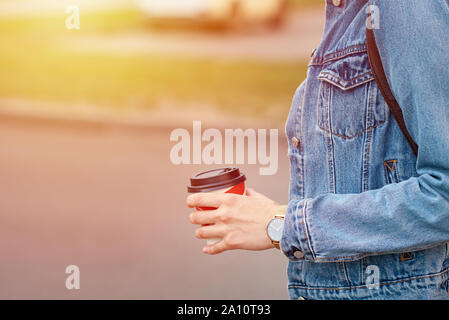Woman hand with paper cup of coffee take away in city street Stock Photo