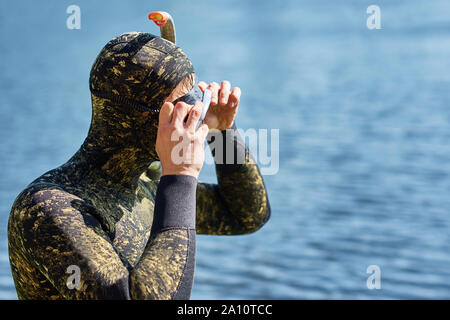 Close up of diver in wet suit with mask and snorkel prepare get ready to dive in water Stock Photo