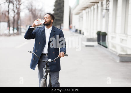 Modern businessman drinking water, going to office by bicycle Stock Photo