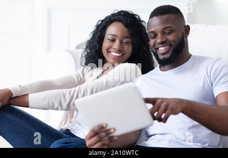 Cheerful african american couple using digital tablet watching funny videos Stock Photo