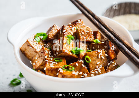 Fried tofu in teriyaki sauce in a white bowl. Vegan food concept.