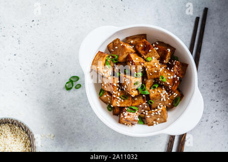 Fried tofu in teriyaki sauce in a white bowl. Vegan food concept. Stock Photo