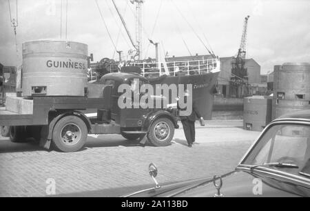 Shipping Guinness beer in giant metal beer kegs (transportable tanks) by truck to the docks to be loaded on to ships by fork-lift trucks, Dublin, Eire c. 1955 Stock Photo