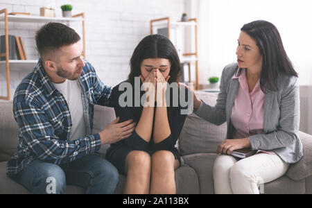 Husband and psychologist comforting crying upset woman Stock Photo