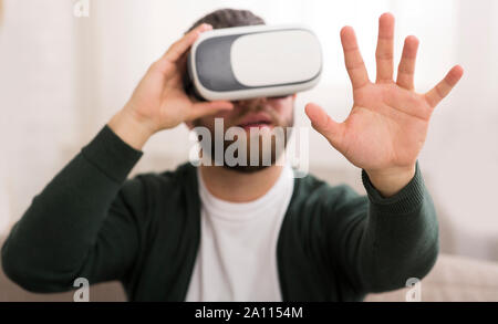 Man using vr glasses at home, looking at his hand Stock Photo