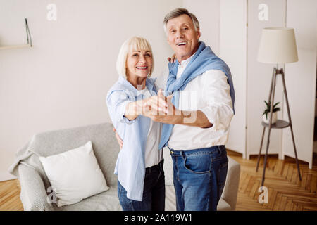 Elderly couple dancing together in the living room Stock Photo