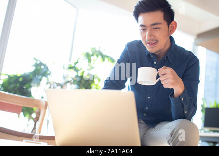 Young man using laptop and drinking coffee Stock Photo
