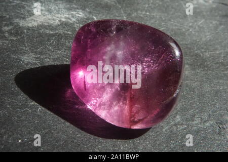 Macro shooting of purple fluorite tumbled pebble on gray slate background Stock Photo