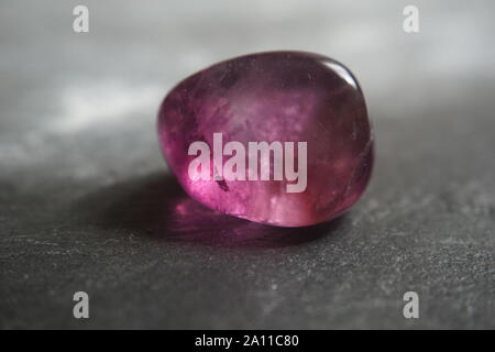 Macro shooting of purple fluorite tumbled pebble on gray slate background Stock Photo