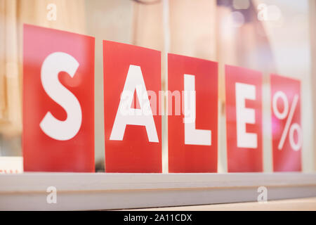 Closeup of red SALE sign on showcase display in shopping mall, copy space Stock Photo