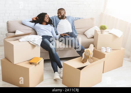 Couple On Sofa Taking Break From Unpacking On Moving Day Stock Photo