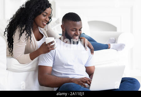 Black couple web surfing on laptop while sitting at home Stock Photo