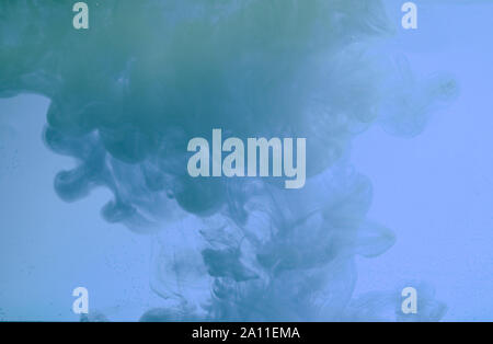Color drop in water, photographed in motion. Ink swirling. Cloud of silky ink under water on blue background. Colorful ink in water, ink drop Stock Photo