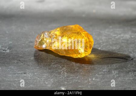 Amber stone  on gray slate background, lit by the sun Stock Photo