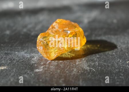 Amber stone  on gray slate background, lit by the sun Stock Photo