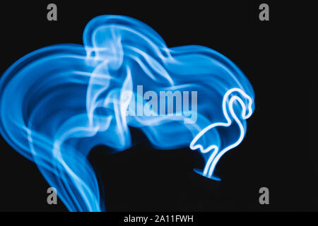 Neon blue flamingo LED lamp with wave in motion as blurred abstract background on black. Stock Photo