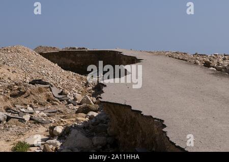 Side of broken asphalt road collapsed and fallen caused by sinkholes near the Dead Sea, Israel. Israel sits on an active geologic fault line ('Syrian-African'), with predictions of a serious earthquake and aftermath tremors that could ravage the country at any moment, Stock Photo