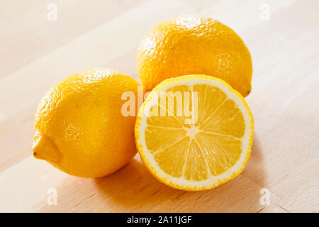 Lemons on a wooden surface, whole and half Stock Photo