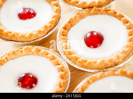 Bakewell tarts in foil case close up on a wooden surface Stock Photo
