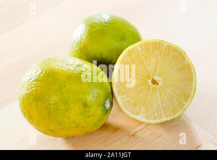 Limes on a wooden table, whole and half Stock Photo