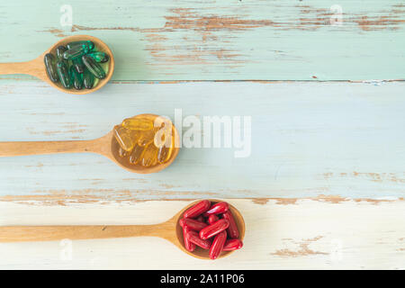 Assorted pharmaceutical medicine pills, tablets and capsules on wooden spoons on vintage wooden table for medicine background Stock Photo