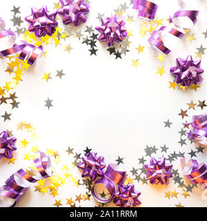 Christmas frame of silver and pink pastel decoration, streamers, tinsel, star, glitter golden light on white. Xmas. Flat lay style. Top view with copy Stock Photo
