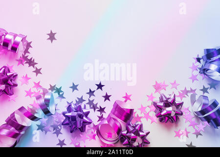 Christmas frame of silver and pink pastel decoration, streamers, tinsel, star, neon gradient on white. Xmas. Flat lay style. Top view with copy space. Stock Photo