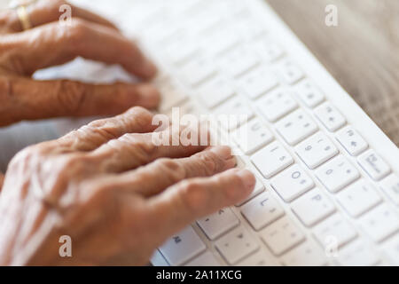 Elderly woman typing on a PC keyboard Stock Photo