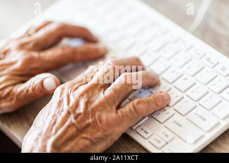 Elderly woman typing on a PC keyboard Stock Photo