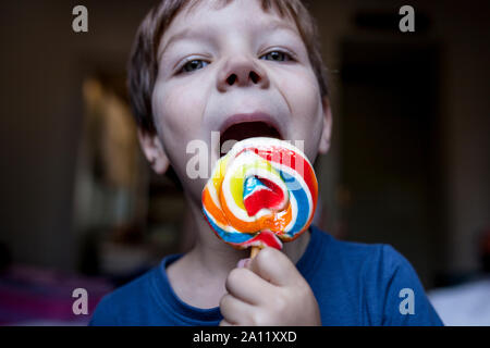 4 years old child boy licking a big colorful  lollipop. Selective focus. Unhealthy food for children concept Stock Photo