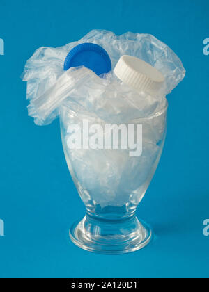 Glass with plastic inside on blue background - drinking plastic environmental concept Stock Photo