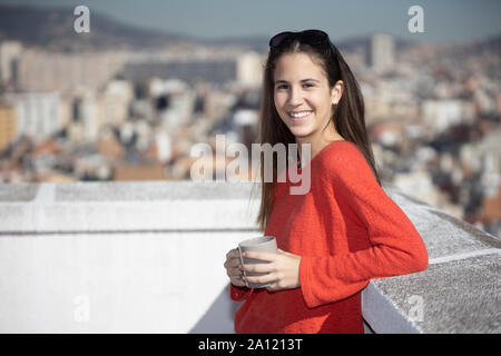 Chica adolescente tomando un café mirando a la cámara en la azotea Stock Photo