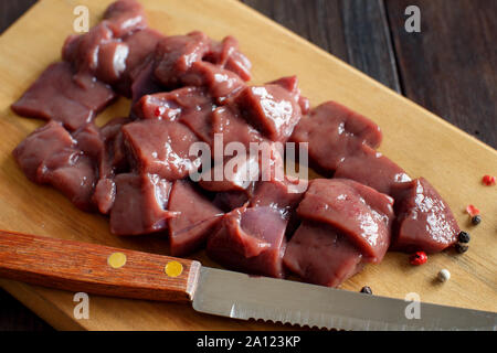 Raw beef liver with knife on a wooden table Stock Photo