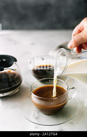 Morning coffee concept. Pouring a milk into morning cup of coffee Stock Photo