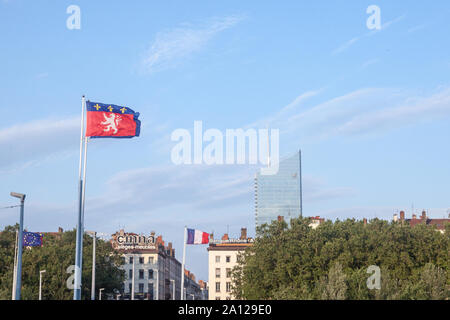 LYON, FRANCE - JULY 14, 2019: Flag of Lyon waiving in front of Tour Incity tower, a business symbol of the city and the highest skyscraper high rise b Stock Photo