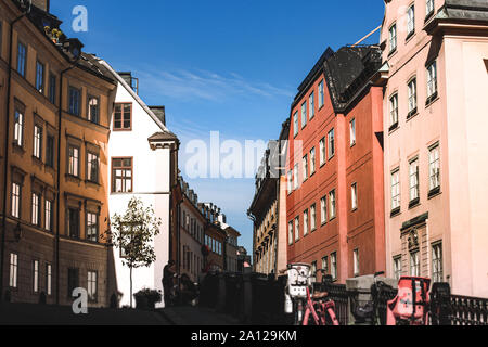 View from below on the roofs of a cozy narrow medieval street yellow orange red buildings facades in Gamla stan, Old Town of Stockholm, Sweden with br Stock Photo
