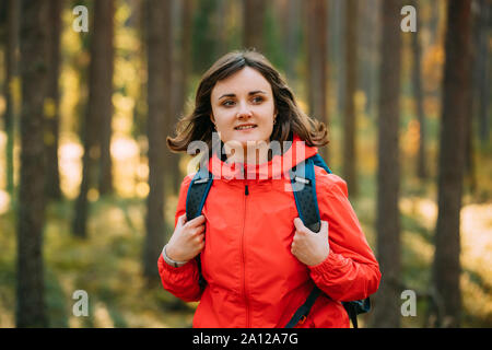Portrait Of Active Young Adult Beautiful Caucasian Girl Woman Dressed In Red Jacket Walking In Autumn Forest. Active Lifestyle In Nature. Stock Photo